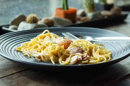 The spaghetti, fried cheese on a black plate on the table.の写真素材