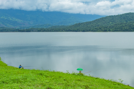 Fishermen sit fishing at the Huai Pa Daeng Reservoir , Phetchabun in  Thailand.の写真素材