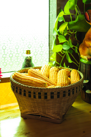 Yellow corn In the bamboo basket on a wooden tableの写真素材