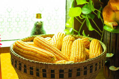 Yellow corn In the bamboo basket on a wooden table