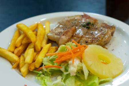 Chicken steak with French fries and salad.の写真素材