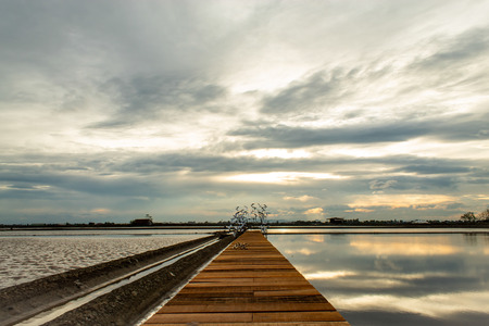 Sunset light reflects from the surface of the water and the wooden bridge.の写真素材