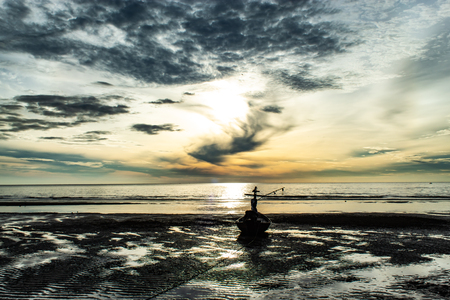 The morning sun light in the sea, and the boat on the beach.の写真素材