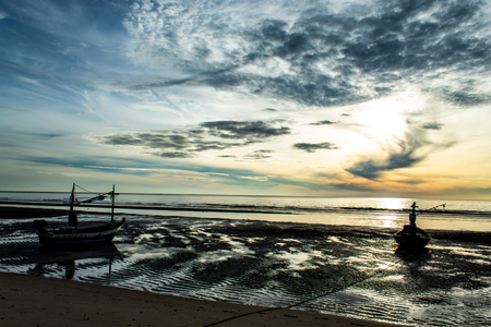 The morning sun light in the sea, and the boat on the beach.の写真素材