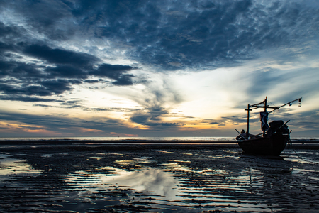 The morning sun light in the sea, and the boat on the beach.の写真素材