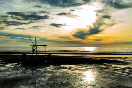The morning sun light in the sea, and the boat on the beach.の写真素材