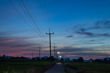 The light of sunset behind the mountain and the high voltage poles.の写真素材