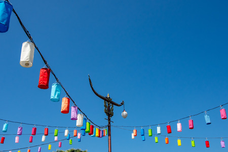 Light poles and lamp with colorful paper on a bright blue sky.の写真素材