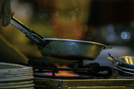 Stainless steel pan on the stove with a yellow flame.の写真素材