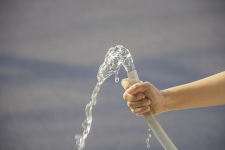Hand boy holding the rubber tube and the water flows outの写真素材