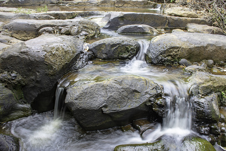 The water flowing over rocks and trees down a waterfall at Khao Ito waterfall , Prachin Buri in Thailand.の写真素材