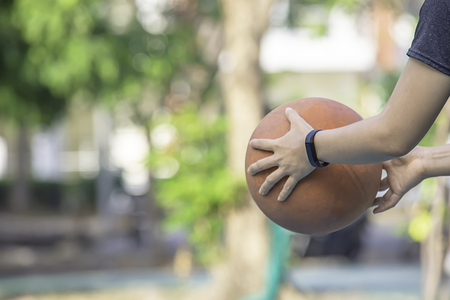 Hand of a woman wearing a watch And holding old basketball .の写真素材