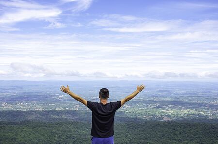Asian man raise their arms on the point of view of the mountains at Patio stone button in Phu Hin...