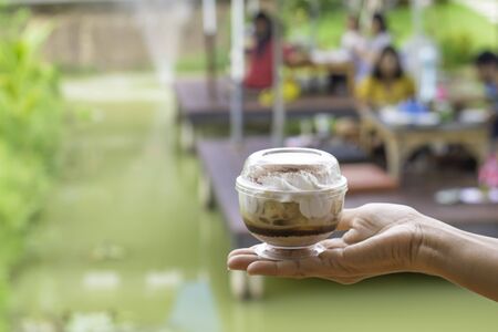 Hand holding cake Background blur people and tree in garden on pond.