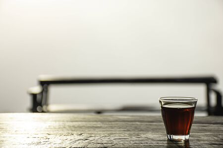 A glass of black coffee on a wooden table Background fog  and morning sunlight.の写真素材