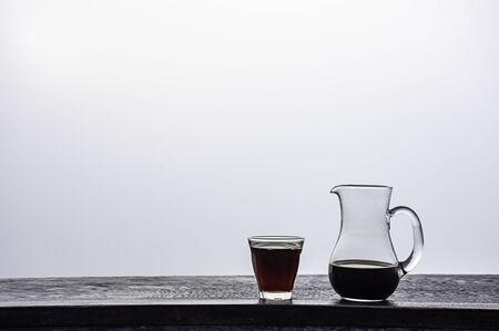 A jug and a glass of black coffee on a wooden table Background fog.の写真素材