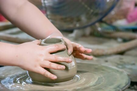 The fingers are shaped clay pot on a rotating tray.の写真素材