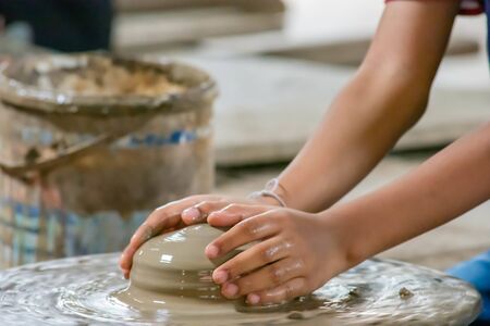The fingers are shaped clay pot on a rotating tray.の写真素材