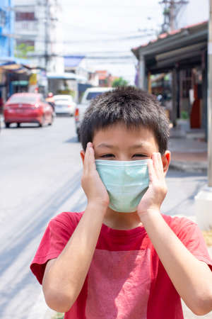 The hand holding the mask on Asian boy face  on the street in Bangkok ,Thailand.