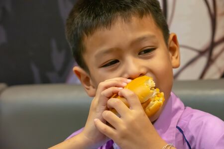 Hamburger fish in hand asia boy holding the eating.の写真素材