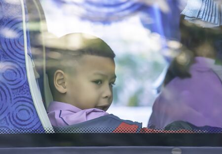 Asian boy sitting on a school bus.の写真素材