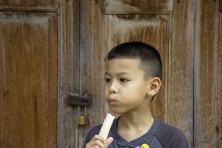 boy was eating bread Background wall of wood.の写真素材