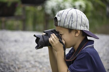 Hand boy holding the camera Taking pictures in park.の写真素材