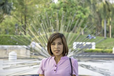 Portrait of Women with short hair brown Background Trees and grass that are blurry.