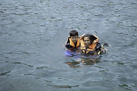 Woman and boy wearing a life jacket, scuba diving in the sea.の写真素材