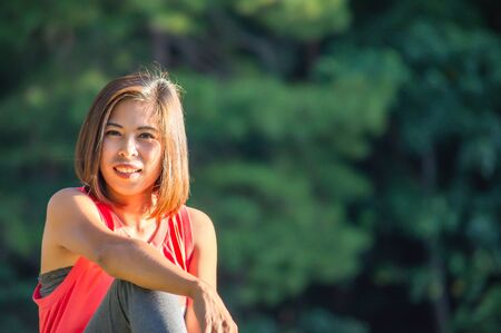 Portrait Asian woman sitting Background blurry treesの写真素材
