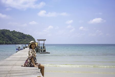 Women Wear a hat on the wooden bridge pier boat in the sea and the bright sky at Koh Kood, Trat in Thailand.の写真素材
