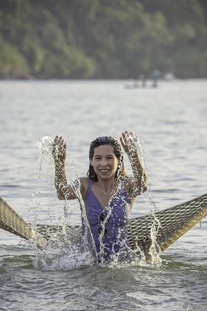 Portrait of Asian woman wearing a swimsuit on Hammock swing in sea.の写真素材