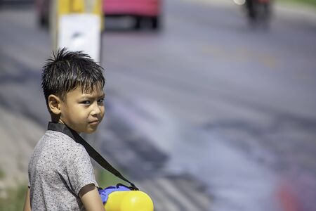 Asian boy holding a water gun play Songkran festival or Thai new year in Thailand.の写真素材