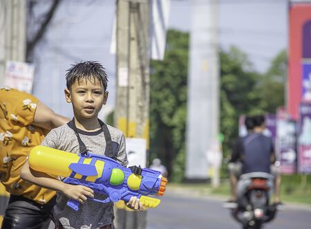 Asian boy holding a water gun play Songkran festival or Thai new year in Thailand.の写真素材