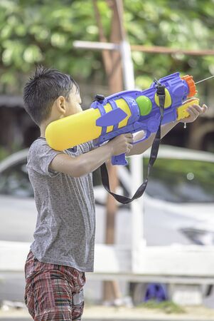 Asian boy holding a water gun play Songkran festival or Thai new year in Thailand.の写真素材
