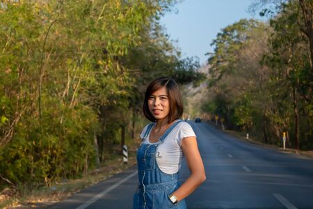 The woman standing on the road, with nature trails green.