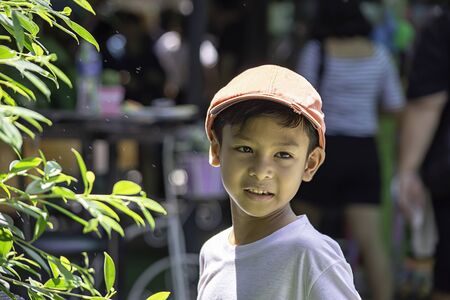 Portrait of Asian boy wearing a red cap and white  shirt is smile and Play water mist.の写真素材
