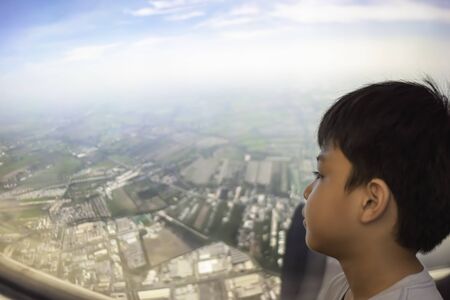 Portrait Asian boy looked at the view outside the plane window Background  City and the sky viewの写真素材