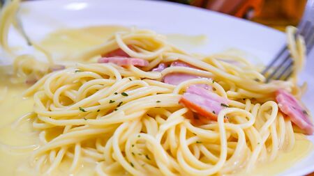 The spaghetti carbonara with fried cheese in a white plate on the table.の写真素材