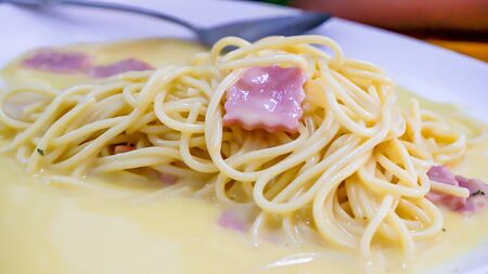 The spaghetti carbonara with fried cheese in a white plate on the table.の写真素材