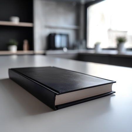 Black leather book on a white table in a modern kitchen interior.の素材