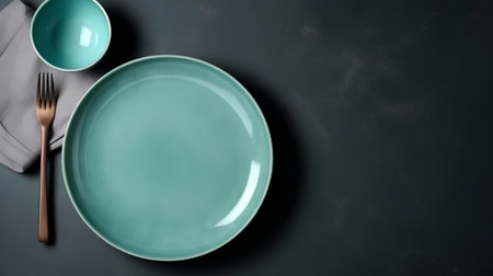 Empty green plate with fork and knife on dark background, top viewの素材