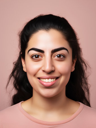 Portrait of a beautiful young woman smiling on a pink background.の素材