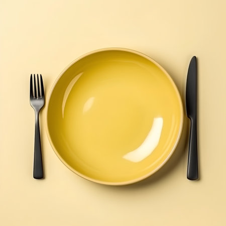 Empty yellow plate with fork and knife on yellow background, top viewの素材