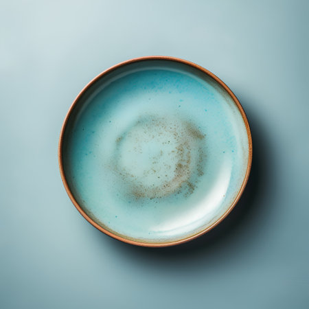 Empty ceramic plate on blue background. Top view. Copy space.の素材