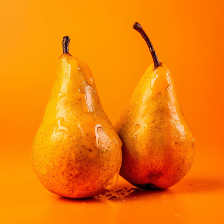 Ripe pears on a bright orange background with drops of waterの素材