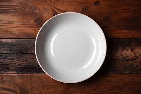 Empty white plate on wooden background. Top view with copy space.の素材
