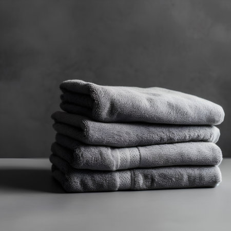 Stack of clean folded gray towels on grey background. Toned.の素材