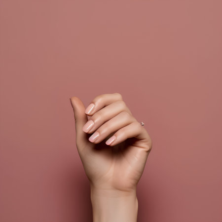 Female hand with beige nail design. Nail polish manicure. Female hand with perfect manicure on pink background.の素材