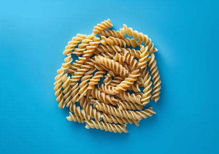 Fusilli pasta spiral on blue background. Top view. Flat layの素材
